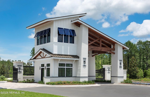 view of front facade with metal roof, brick siding, board and batten siding, and a standing seam roof