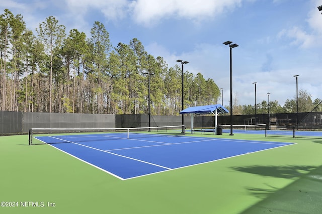 view of tennis court featuring community basketball court and fence