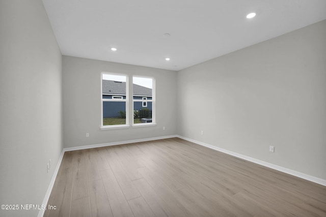 unfurnished room with recessed lighting, wood finished floors, and baseboards