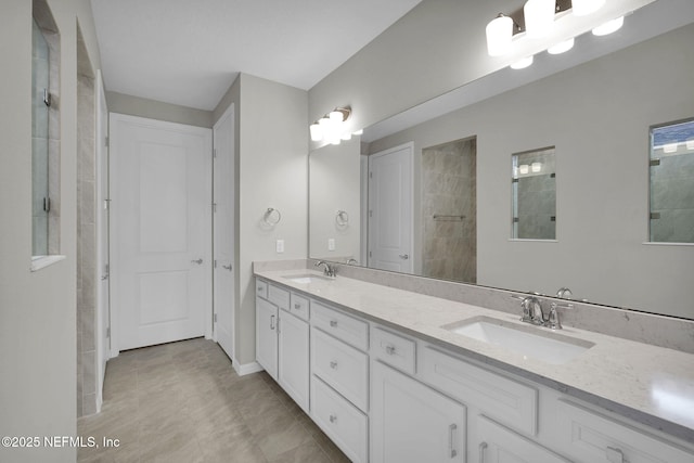 bathroom with double vanity, tiled shower, and a sink