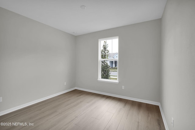 spare room featuring baseboards and wood finished floors