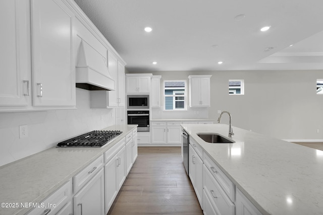 kitchen featuring custom range hood, a sink, white cabinetry, recessed lighting, and stainless steel appliances