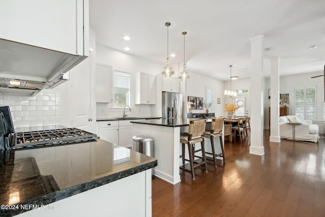 kitchen with white cabinetry, stainless steel refrigerator with ice dispenser, a breakfast bar area, decorative light fixtures, and dark wood-type flooring