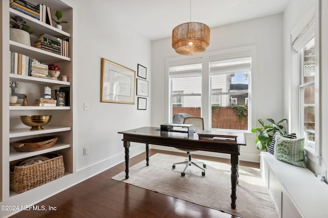 office with a wealth of natural light, built in features, and dark hardwood / wood-style flooring