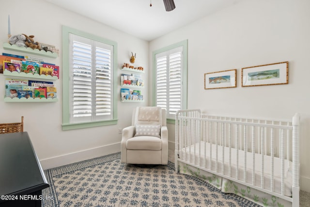 carpeted bedroom with ceiling fan and a nursery area