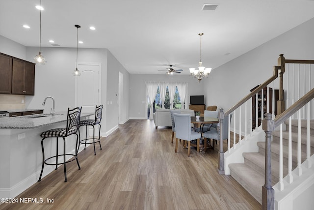 dining space featuring light hardwood / wood-style flooring, sink, and ceiling fan with notable chandelier