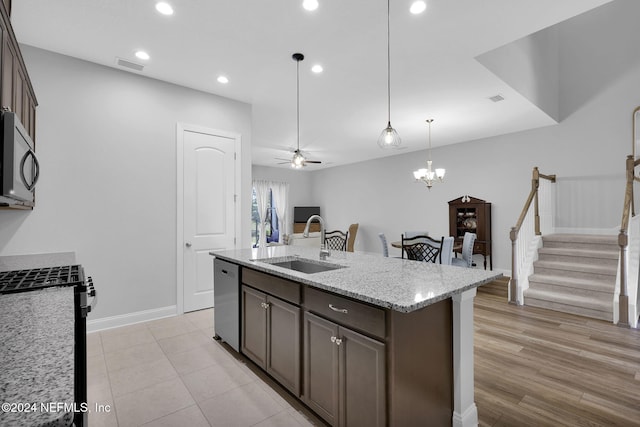 kitchen featuring light stone countertops, sink, appliances with stainless steel finishes, ceiling fan with notable chandelier, and light hardwood / wood-style flooring