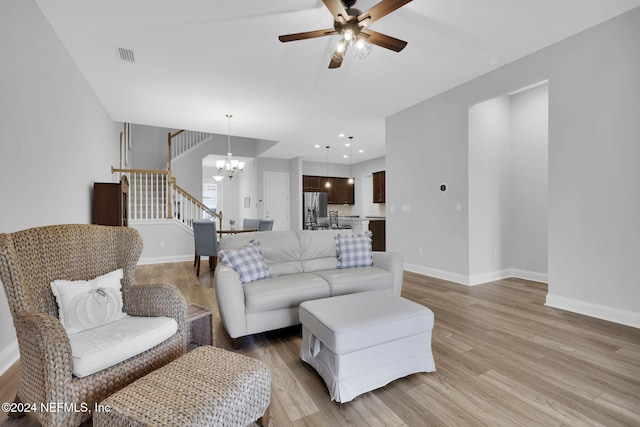 living room with light hardwood / wood-style flooring and ceiling fan with notable chandelier