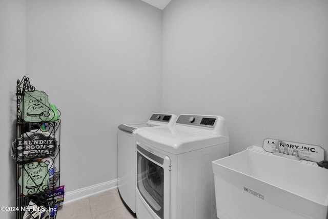 laundry area featuring washer and dryer, light tile patterned flooring, and sink