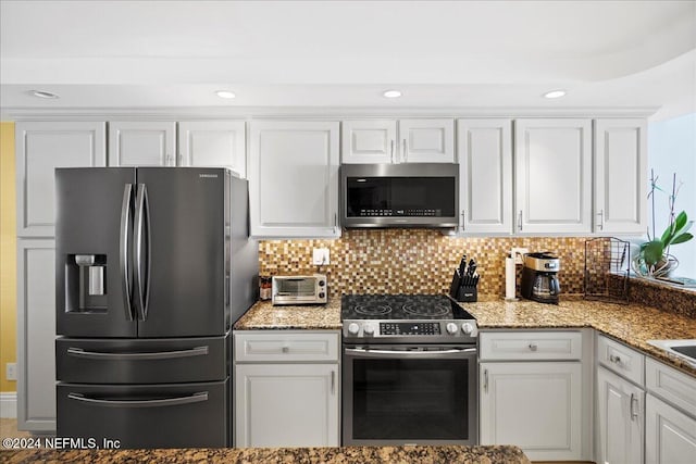 kitchen featuring dark stone counters, tasteful backsplash, white cabinetry, and stainless steel appliances