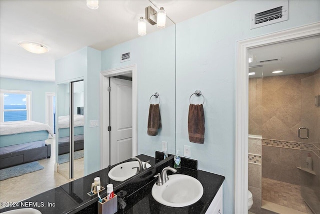 bathroom featuring toilet, tiled shower, tile patterned floors, and vanity