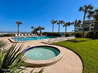 view of swimming pool featuring a yard and a hot tub