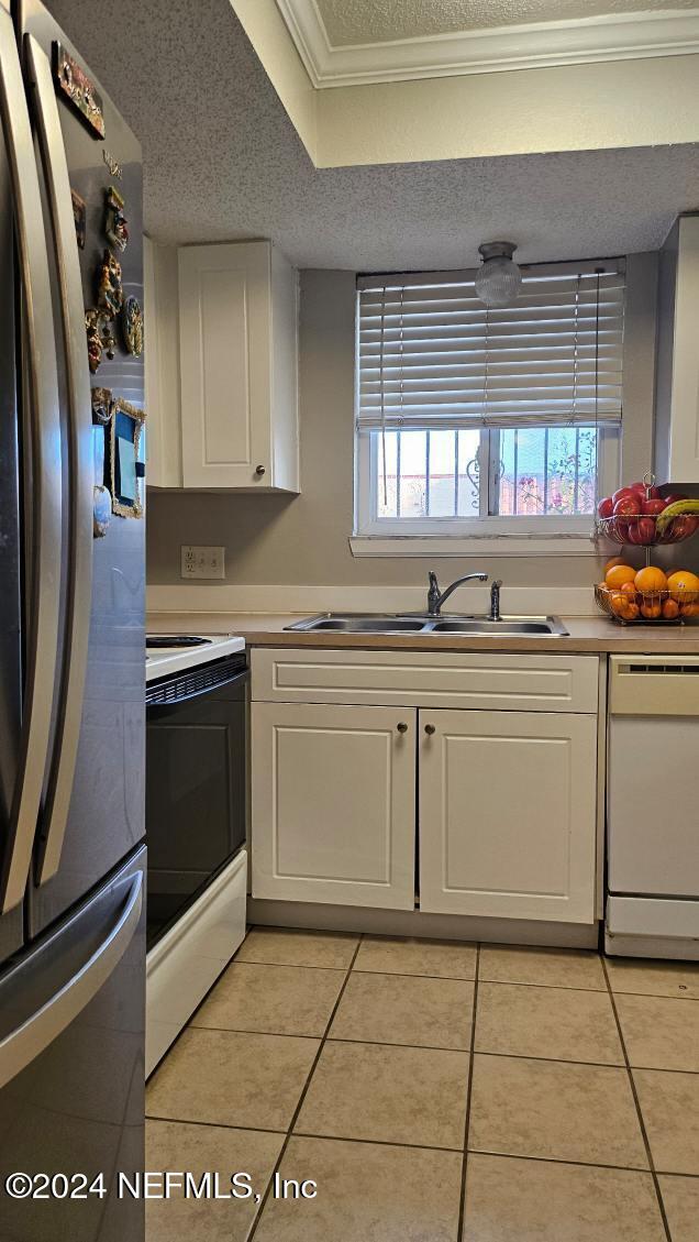 kitchen with white cabinets, a wealth of natural light, sink, and white appliances