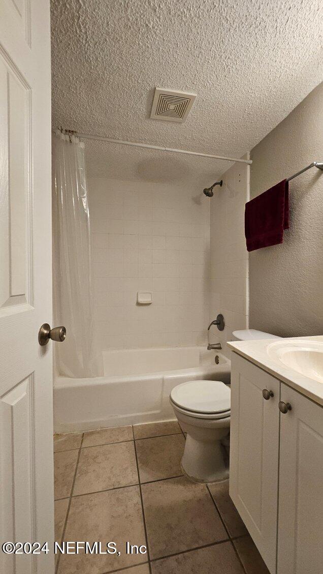 full bathroom with toilet, shower / bath combo, vanity, and tile patterned floors