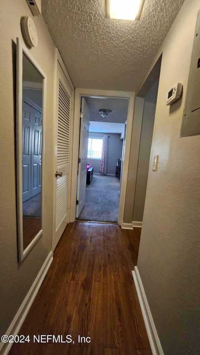 hallway featuring a textured ceiling and dark hardwood / wood-style flooring