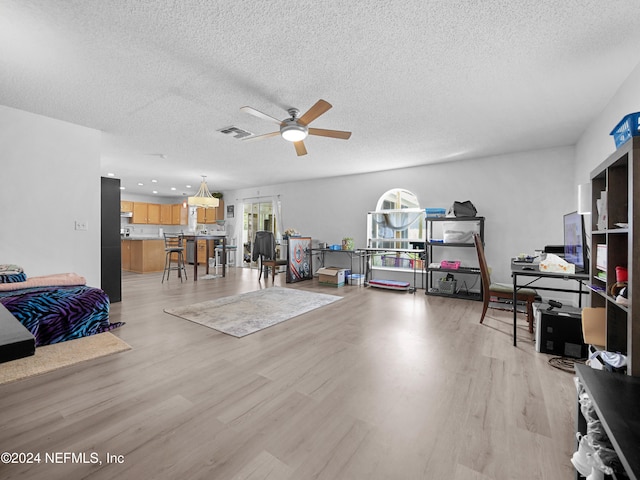 miscellaneous room with ceiling fan, a textured ceiling, and light wood-type flooring