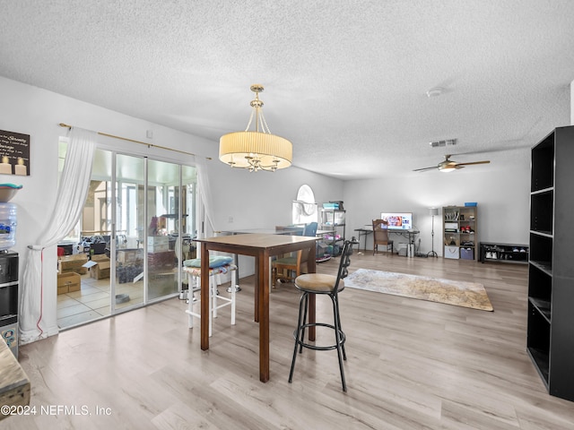 dining room featuring a textured ceiling, ceiling fan, wood-type flooring, and a wealth of natural light