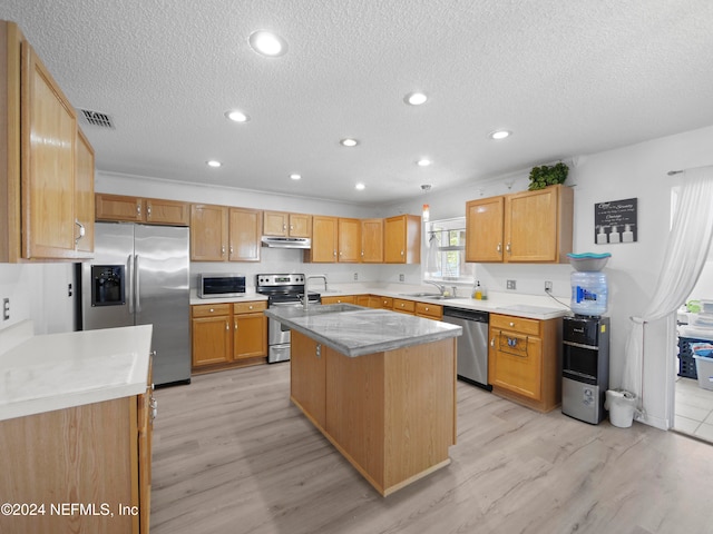 kitchen featuring appliances with stainless steel finishes, a textured ceiling, sink, light hardwood / wood-style floors, and a center island