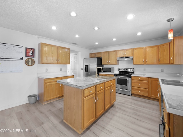 kitchen with appliances with stainless steel finishes, light hardwood / wood-style flooring, pendant lighting, and a kitchen island