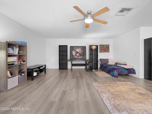 bedroom with a textured ceiling, light wood-type flooring, and ceiling fan