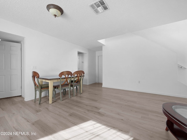 dining area with a textured ceiling and light wood-type flooring