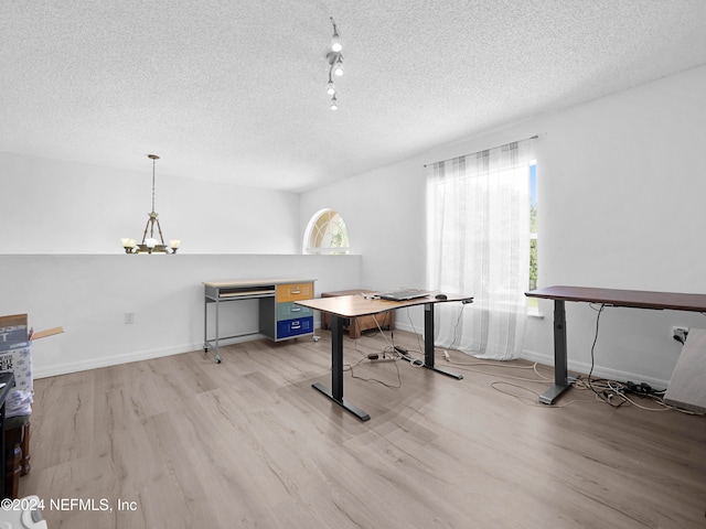 office space featuring light hardwood / wood-style flooring, a notable chandelier, a textured ceiling, and rail lighting