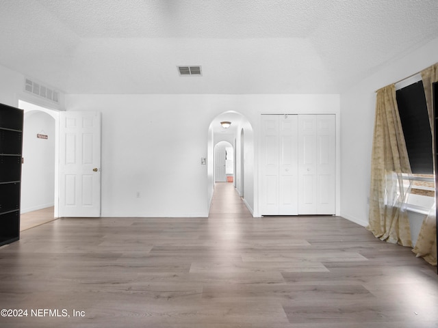 spare room featuring light hardwood / wood-style flooring and a textured ceiling