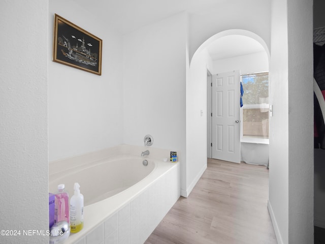 bathroom with tiled tub and hardwood / wood-style floors