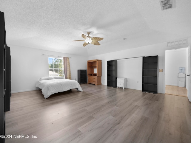 bedroom featuring light hardwood / wood-style flooring, a textured ceiling, and ceiling fan