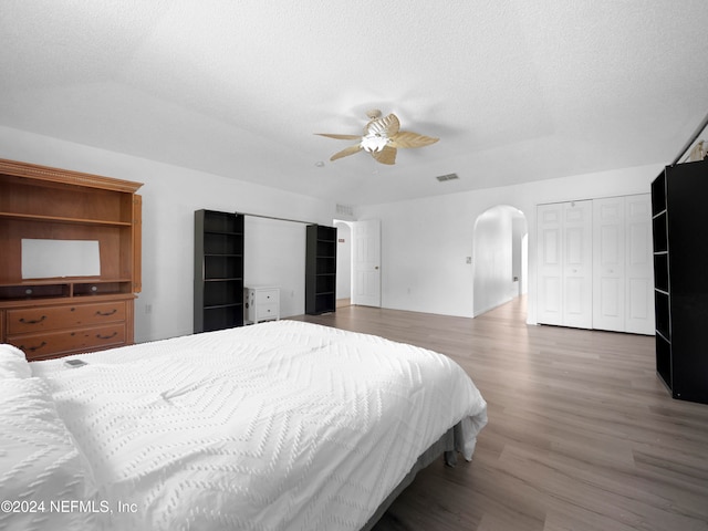 bedroom with ceiling fan, hardwood / wood-style flooring, and a textured ceiling