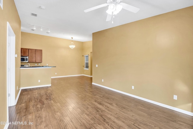 unfurnished living room with rail lighting, wood-type flooring, and ceiling fan