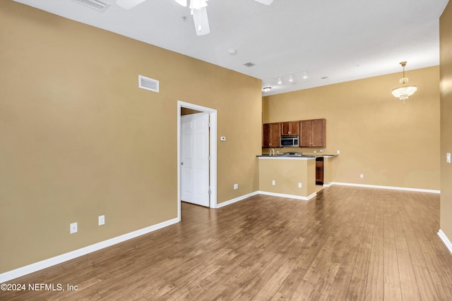 unfurnished living room with hardwood / wood-style flooring, ceiling fan, and rail lighting