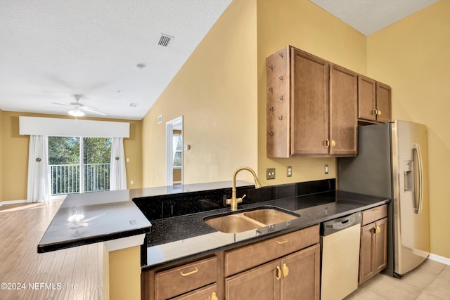 kitchen with dark stone counters, sink, dishwasher, lofted ceiling, and light hardwood / wood-style flooring