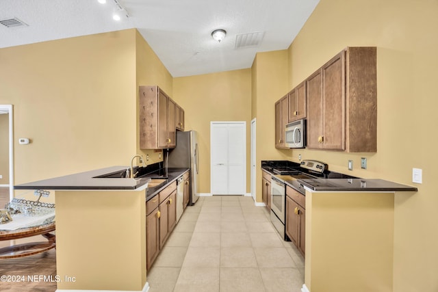 kitchen featuring kitchen peninsula, appliances with stainless steel finishes, a textured ceiling, and a kitchen bar