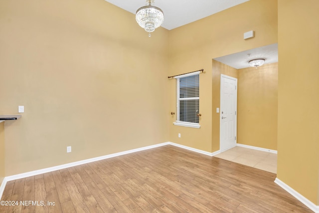 spare room featuring light hardwood / wood-style flooring and an inviting chandelier