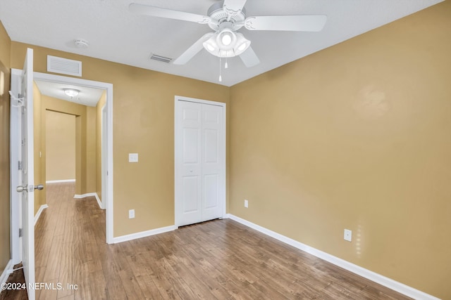 unfurnished bedroom featuring light hardwood / wood-style floors, ceiling fan, and a closet