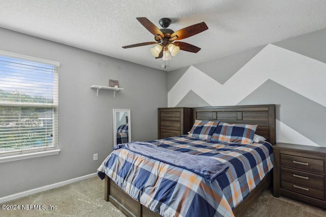 carpeted bedroom with ceiling fan, a textured ceiling, and a walk in closet