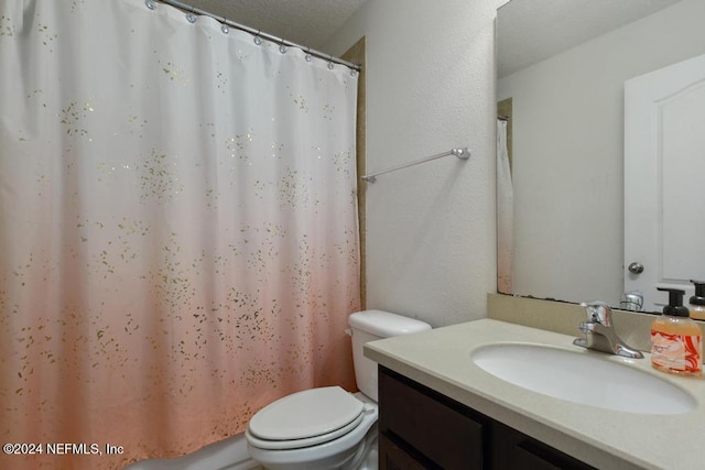 bathroom with walk in shower, vanity, toilet, and a textured ceiling