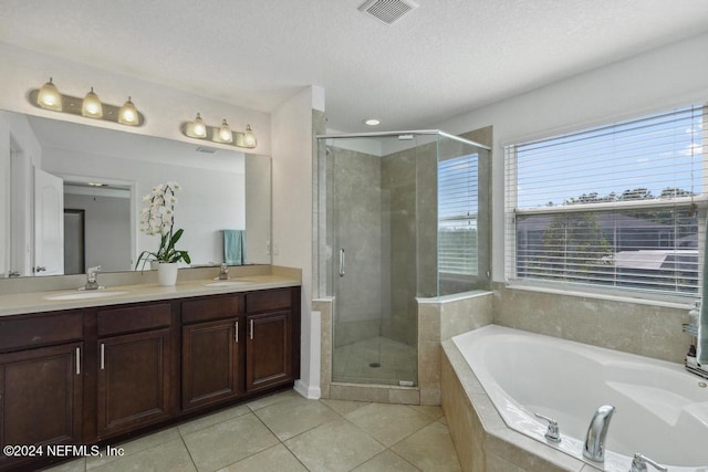 bathroom with tile patterned flooring, vanity, a textured ceiling, and separate shower and tub