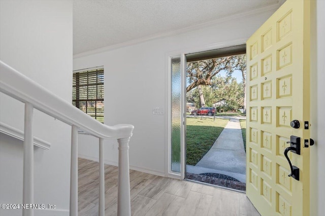 foyer entrance featuring crown molding, a textured ceiling, a healthy amount of sunlight, and light hardwood / wood-style flooring