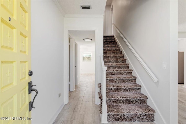 stairs with wood-type flooring and ornamental molding