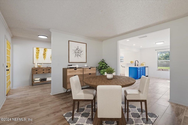 dining room with crown molding, light wood-type flooring, a textured ceiling, and sink