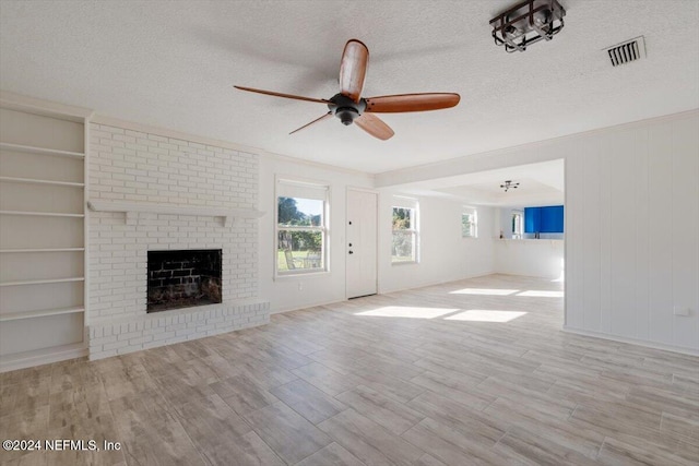 unfurnished living room featuring a brick fireplace, light hardwood / wood-style floors, a textured ceiling, and ceiling fan