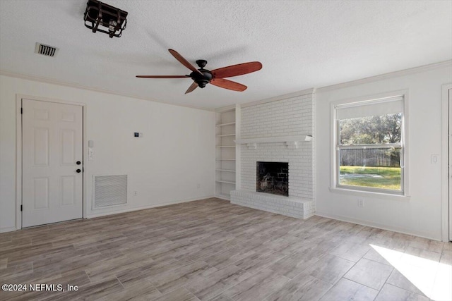 unfurnished living room featuring built in shelves, ceiling fan, a textured ceiling, a fireplace, and light hardwood / wood-style flooring