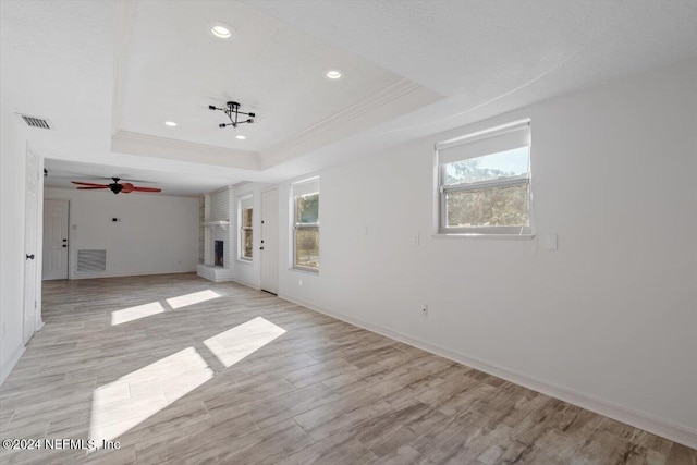 unfurnished room with light wood-type flooring and a tray ceiling