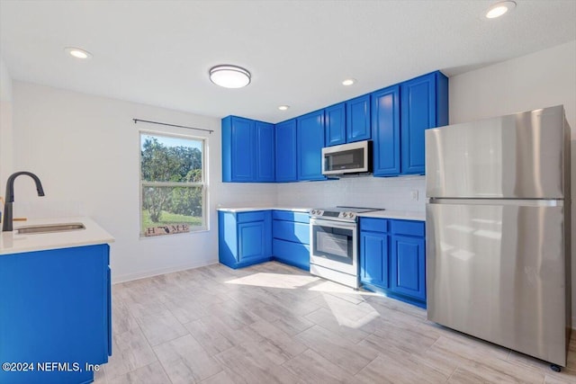 kitchen featuring decorative backsplash, blue cabinetry, appliances with stainless steel finishes, and sink