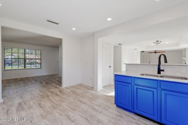 kitchen with light wood-type flooring, decorative backsplash, sink, and crown molding