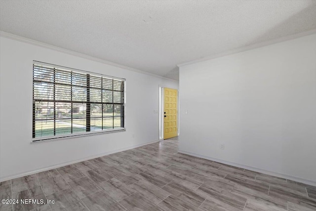 empty room featuring light wood-type flooring, a textured ceiling, and crown molding