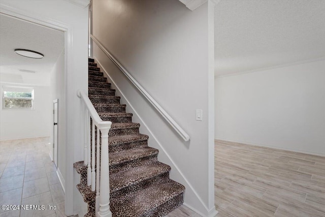 staircase with wood-type flooring and a textured ceiling