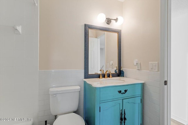 bathroom with tile walls, vanity, and toilet